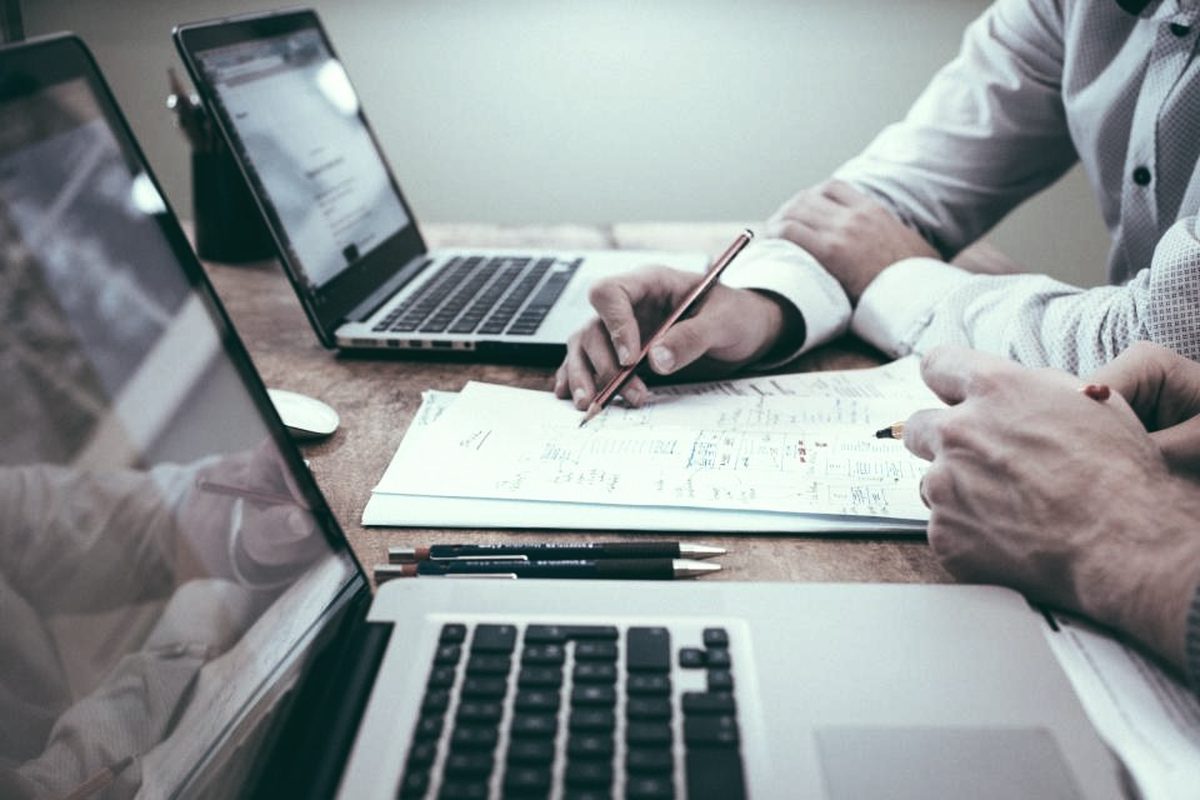 Duas pessoas revisando anotações e planilhas sobre a mesa de trabalho